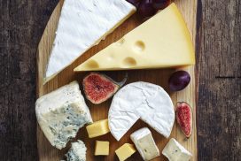 Cheese plate served with grapes, jam and figs on a wooden background