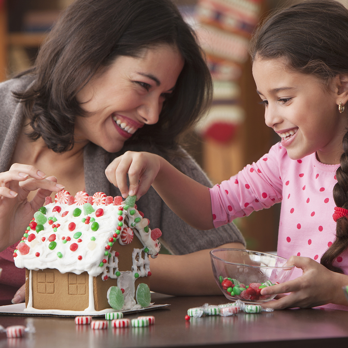 Mother and daughter decorating gingerbread house