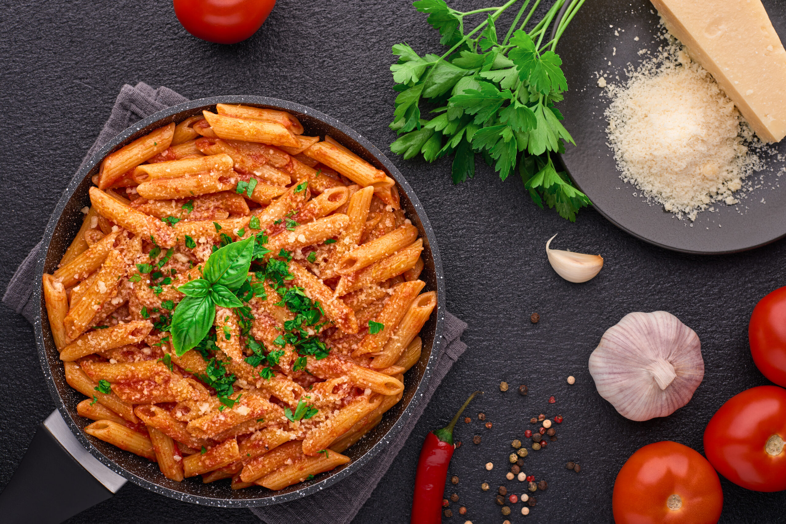 Frying pan with Penne All'arrabbiata pasta cooked according to a traditional Italian recipe and ingredients top view